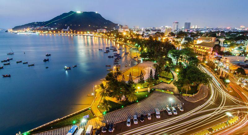 Một du khách đang chụp ảnh “check-in” trên bãi đá tại Bãi Dâu Vũng Tàu, thể hiện sự tương tác với địa hình độc đáo